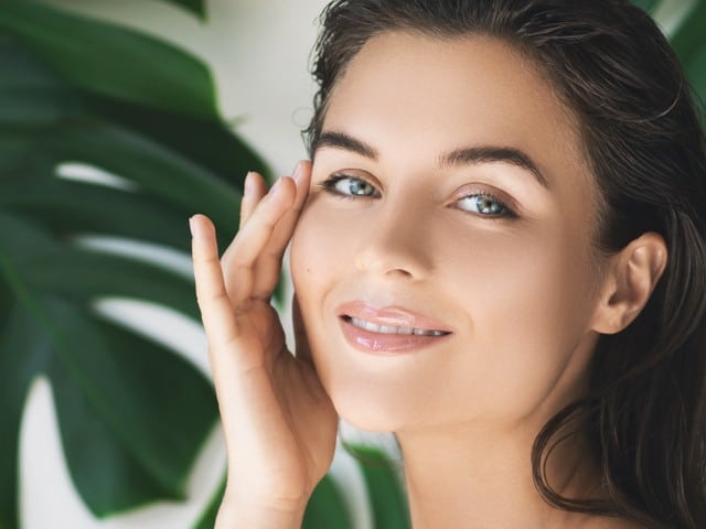 woman with perfect smooth skin in tropical leaves